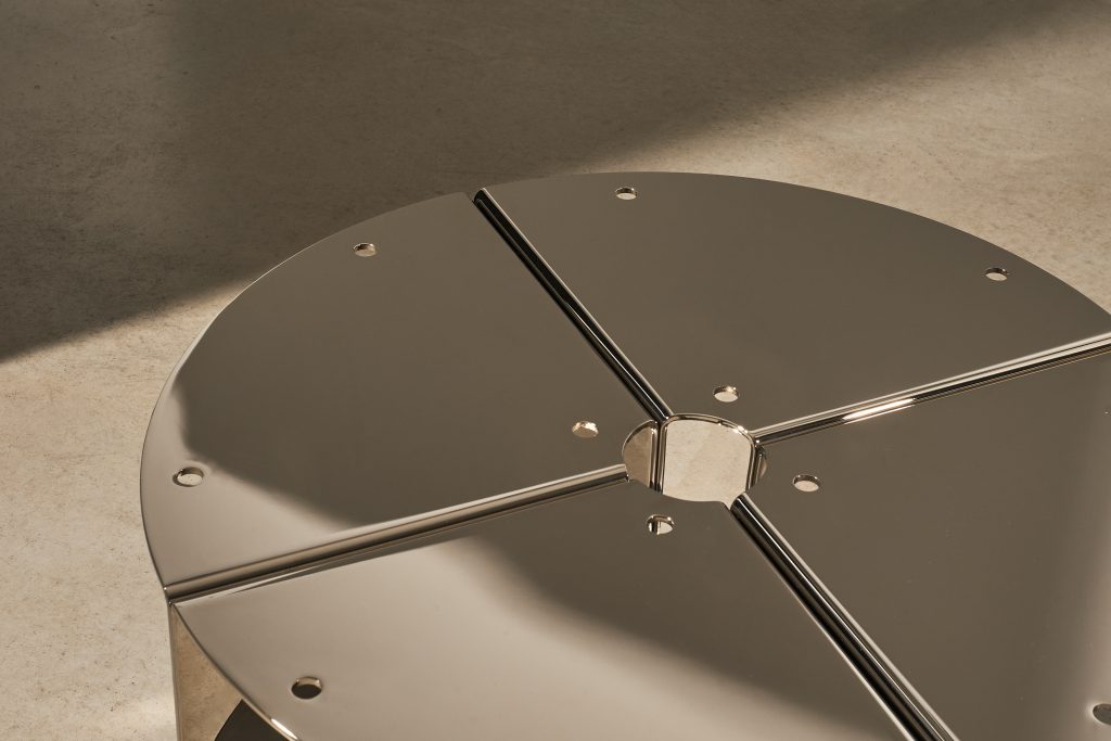 Round nickel-plated aluminium tabletop with cross-shaped seam and circular joints, seen from above
