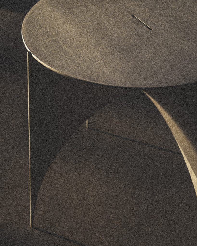 LINO side table in low light: round satin aluminium top on a base folded from a single sheet