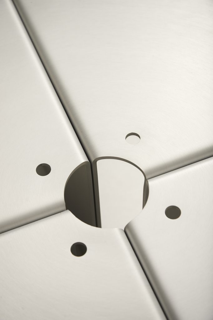 Detail of a satin aluminium joint: four panels meeting at the central circular hub