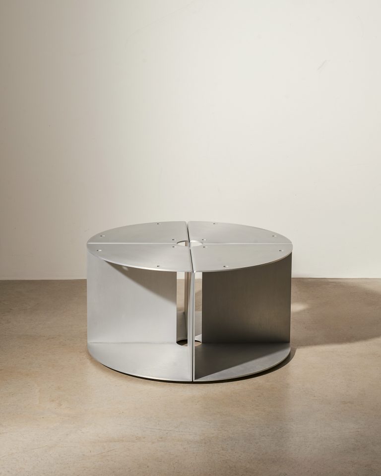 Three satin aluminium modular elements seen from above, with folded profiles and daylight shadows